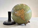 un globe vert posé sur une table à côté d'un bougeoir noir