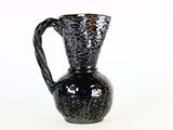 un vase noir posé sur une surface blanche