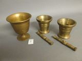 three brass vases and a wooden mallet on a table