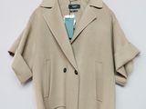 La veste est de couleur beige et est suspendue à un cintre avec une cravate bleue.