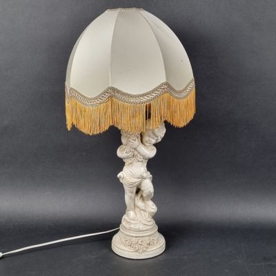 une lampe de table blanche avec un abat-jour blanc orné de franges dorées