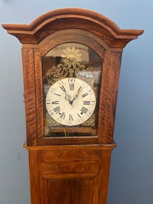 une horloge de parquet en bois dont le cadran est orné de chiffres romains
