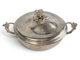 une casserole en argent avec un couvercle, posée sur une surface blanche