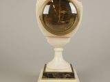 a small white clock with a gold face on a stand