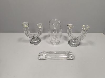 three clear glass candlesticks and a glass tray on a white table