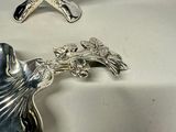 a silver plate with a bird on it next to a silver plate with a bird on it