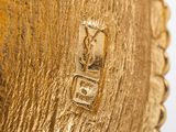 a close up of a gold vase on a white surface