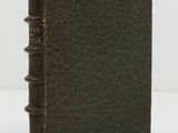 un vieux livre en cuir marron posé sur une table blanche
