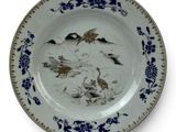 a blue and white plate with birds and flowers on it