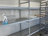 une étagère métallique au milieu d'une cuisine, sur laquelle sont posés de nombreux objets
