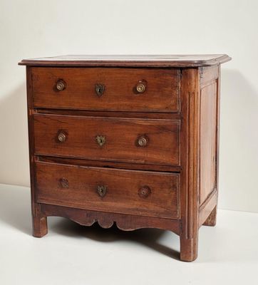 a small wooden chest of drawers on a white background