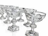 six verres à vin en cristal sont alignés sur une surface blanche
