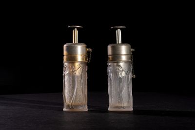 pair of clear glass bottles with gold caps on a black surface