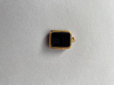 un pendentif en pierre dorée et noire sur un fond blanc