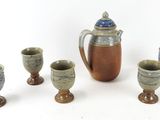 five cups and a pitcher sitting next to each other on a table