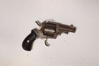 un gros plan d'un revolver posé sur une surface blanche, avec une crosse noire