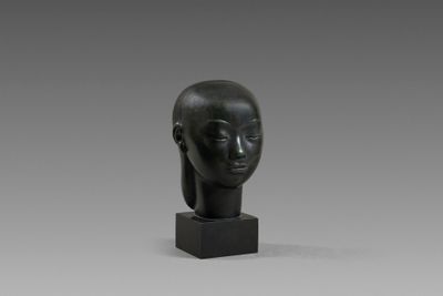 une sculpture noire représentant la tête d'une femme, posée sur un socle noir