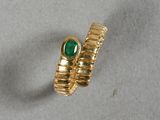 gros plan d'une bague en or avec une pierre verte