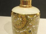un vase blanc et doré, muni d'un couvercle doré, posé sur une table