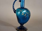 a blue glass vase with a gold leaf design on it