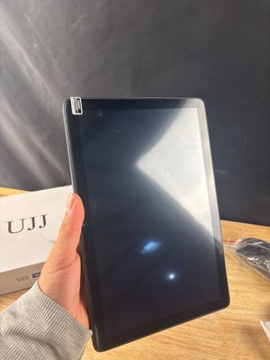 une personne tenant une tablette sur une table, avec une boîte en arrière-plan