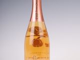 une bouteille de champagne avec une étiquette rose sur fond blanc