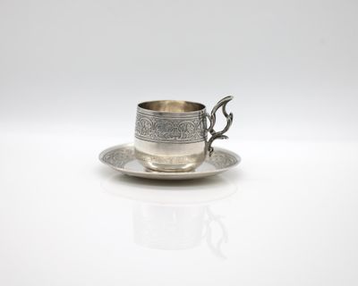 a silver cup and saucer on a saucer on a white surface