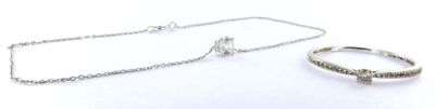 a silver necklace and a silver ring on a white surface