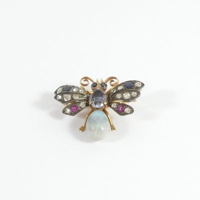 a close up of a bee broochle with a rainbow colored stone