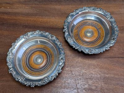 two silver plates sitting on a wooden table