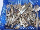 beaucoup de cuillères et de fourchettes en argent dans un panier bleu