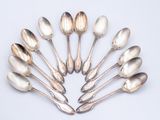 six silver spoons are arranged in a circle on a white surface