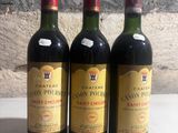 trois bouteilles de vin posées sur une table près d'un mur