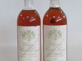 two bottles of wine sitting next to each other on a white surface