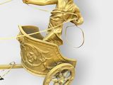 a gold statue of a man riding a horse drawn carriage