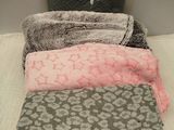 quatre couvertures sur un lit, avec un sac à main posé dessus