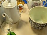 a table with a tea pot, a tea pot, a cup, and a glass on it