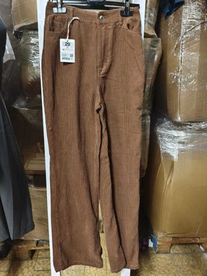 un pantalon en velours côtelé marron suspendu à un cintre devant des cartons