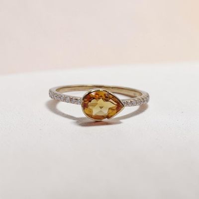 une photo d'une bague en diamant jaune et blanche posée sur une surface blanche