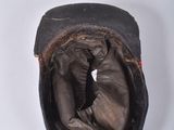 a black hat with a brown leather band on a white surface