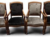 quatre chaises avec des assises recouvertes de velours noir et un piètement en bois