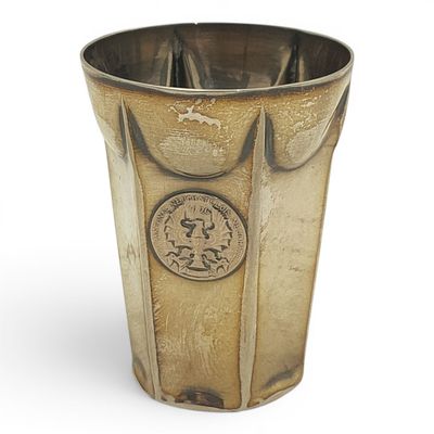 un vase en argent avec une pièce sur le côté