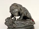 bronze statue of a lion on a rock with a mouse in its mouth