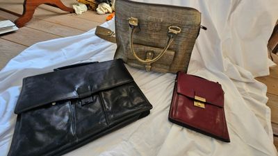 trois sacs à main sont posés sur un lit recouvert d'un drap blanc