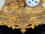 a gold clock sitting on top of a black marble base