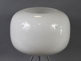 a white vase that is on a stand on a gray background