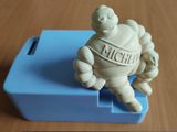 une petite figurine représentant un homme assis sur une boîte bleue