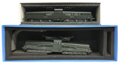 deux trains miniatures posés dans une boîte sur une surface blanche