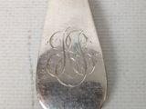 a silver spoon with a monogram on it sitting on a table