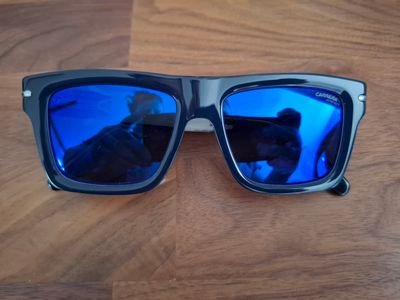 Quelqu'un prend une photo d'une paire de lunettes de soleil posée sur une table en bois.